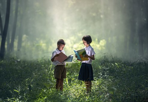 Deux bénéficiaires d'Enfants d'Aise lisant un livre dans une forêt féérique.
